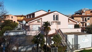 A pink building with a sloped roof, a staircase, and a small white container on the roof. - Palme 8 - Marcelli, three-room apartment with private garden, Residence Le Palme (Marcelli)