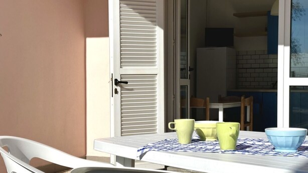 A table with a tablecloth, a chair, and a door with shutters. - Palme 8 - Marcelli, three-room apartment with private garden, Residence Le Palme (Marcelli)