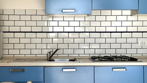 A kitchen with white and blue tiles, a stainless steel sink, and a gas stove. - Palme 8 - Marcelli, three-room apartment with private garden, Residence Le Palme (Marcelli)