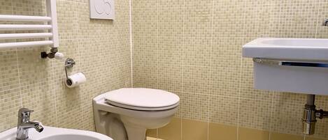 A bathroom with a toilet, bidet, and sink.