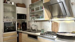 Een moderne keuken met inbouwapparatuur, een roestvrijstalen afzuigkap en een magnetron.