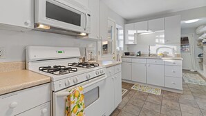 A modern kitchen with white appliances, a gas stove, a microwave, and a built-in oven. - Harmony Guest Home  (Flagstaff)