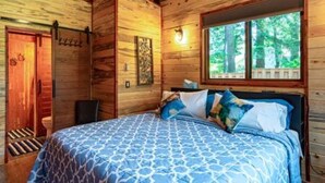 Une pièce dans un chalet en bois, avec un lit, une fenêtre et une porte.