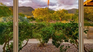A view through a glass door of a garden with various shrubs and a flagpole. - Heated Pool & Hot Tub / 3 BR 2 BA / Big 360º Views (Tucson)