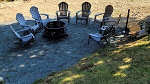 A gravel patio with Adirondack chairs arranged around a central fire pit. - New listing! Perfectly centered in the Birch Harbor village!

 (Gouldsboro)