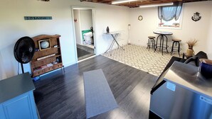 A kitchen with a wooden cabinet, a blue mat, a stainless steel dishwasher, and a small table with stools. - New listing! Perfectly centered in the Birch Harbor village!

 (Gouldsboro)