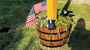 A wooden post with the number 465, a small American flag, and a solar-powered light fixture on a grassy area. - New listing! Perfectly centered in the Birch Harbor village!

 (Gouldsboro)