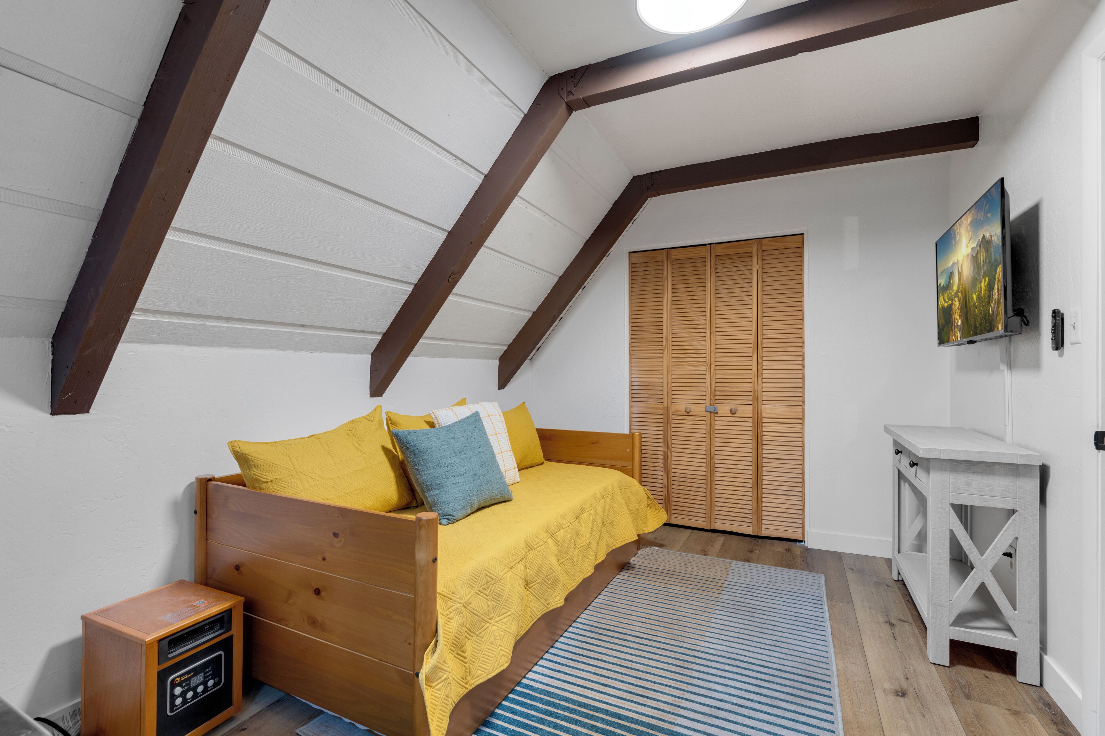 Un dormitorio con una cama de madera, una mesita de noche, un armario y un televisor montado.