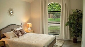 A bedroom with a bed, nightstand, lamp, window with curtains, and a potted plant. - Tropical Family Funhouse, Relax: No Chore Pet friendly Rental (Edinburg)