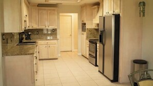 A kitchen with light-colored cabinets, a stainless steel refrigerator, and a countertop with a sink. - Tropical Family Funhouse, Relax: No Chore Pet friendly Rental (Edinburg)
