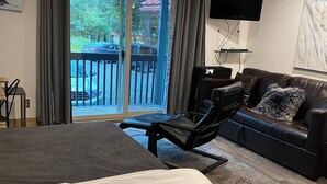 A hotel room with a bed, a sofa, a TV, and a balcony with a view of the outside. - Beautiful Girdwood Condo (Anchorage)