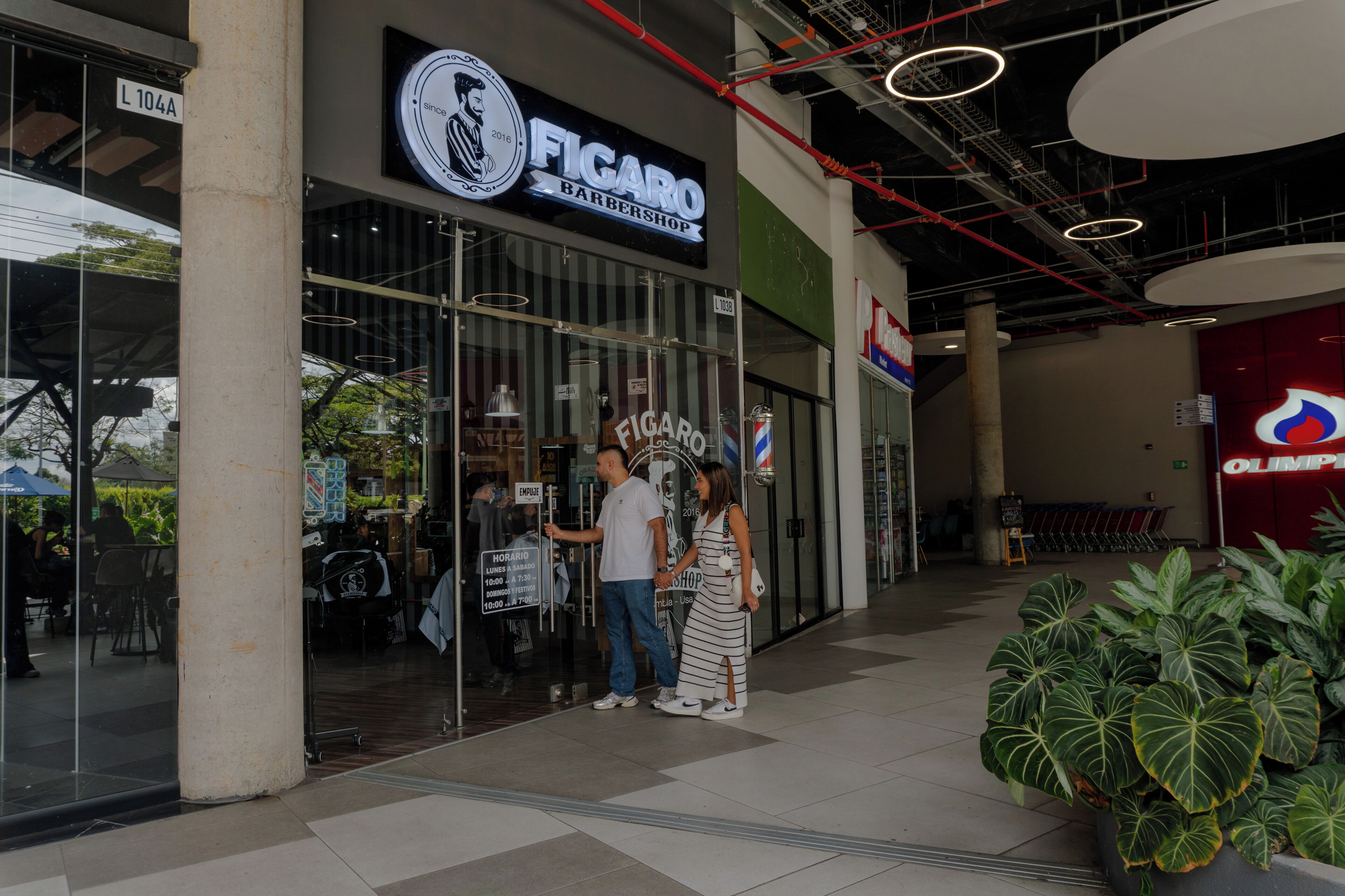 A barbershop with a glass facade, a sign indicating 'Figaro Barbershop,' and a visible entrance.