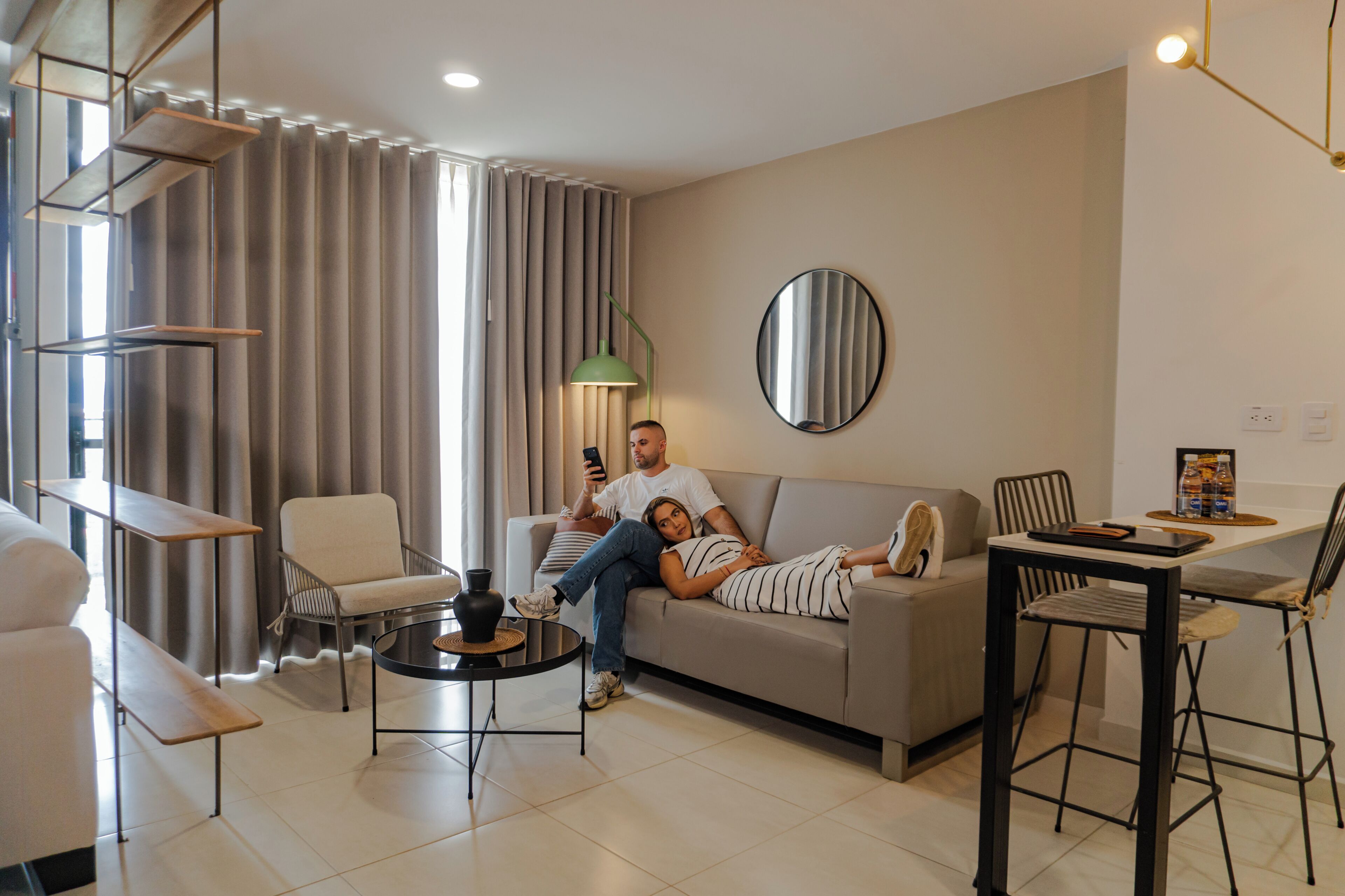 Un salon moderne comprenant un canapé, des fauteuils, une table basse et un coin repas avec une table et des chaises.