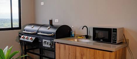 A compact kitchen with a built-in grill, a microwave, and a sink.