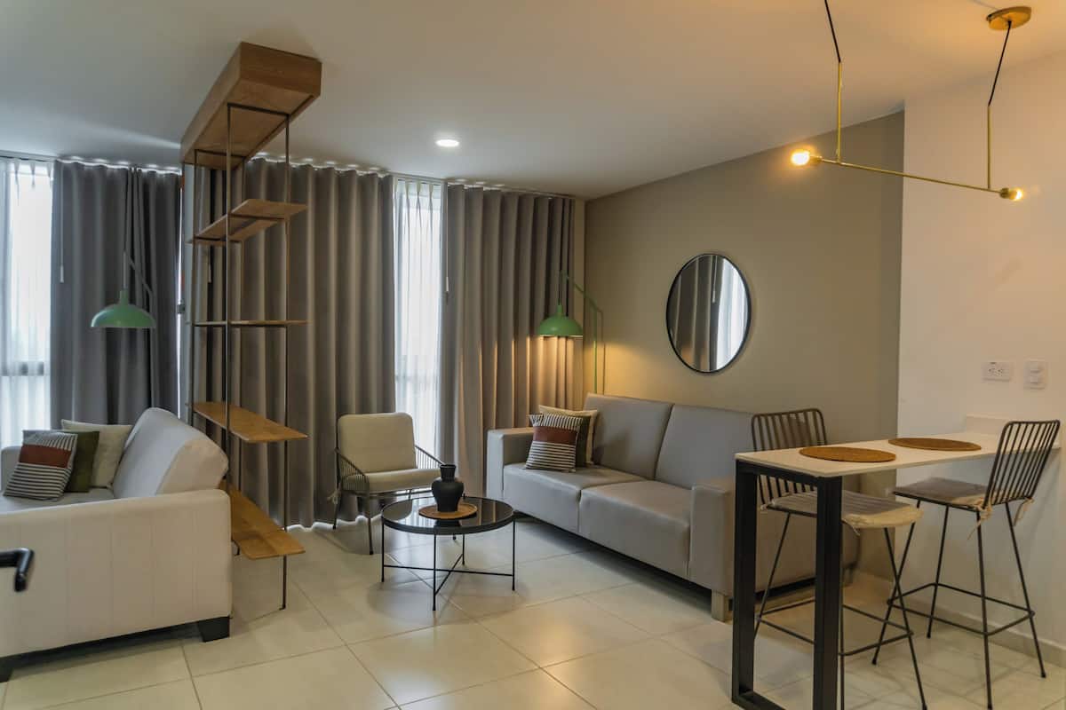 A modern living room with a sofa, chairs, a coffee table, and a dining table.