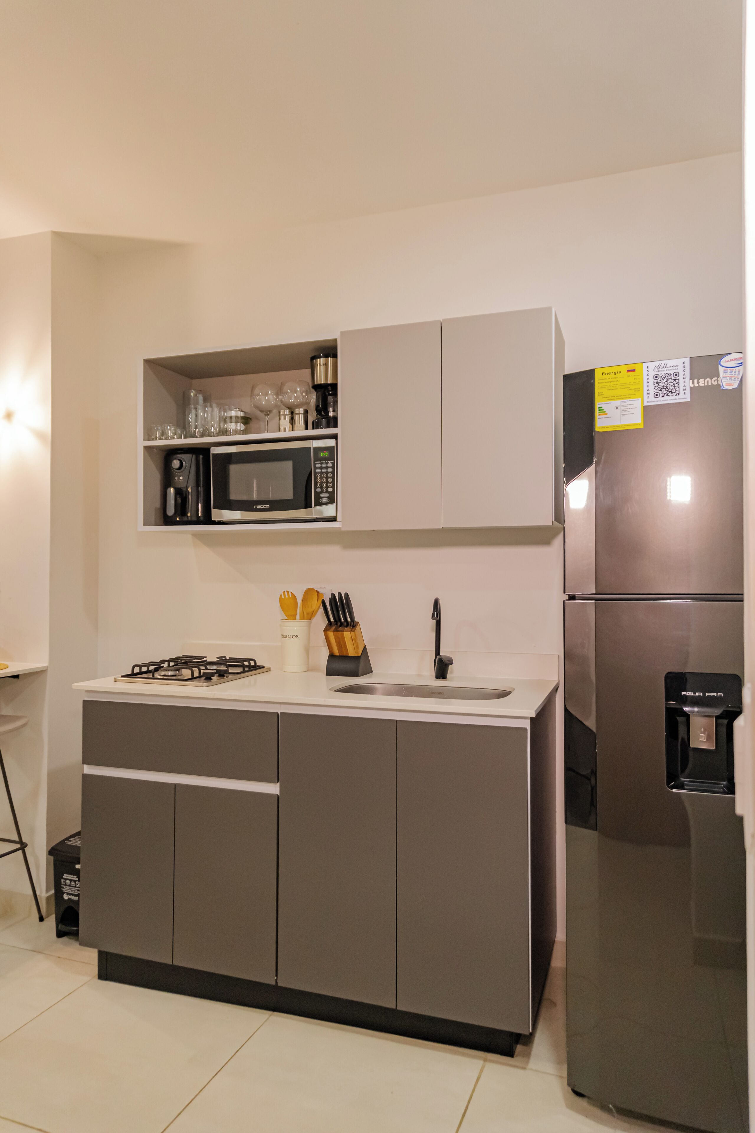 A modern kitchen with a built-in microwave, gas stove, sink, and stainless steel refrigerator.