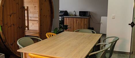 Un comedor con una mesa y sillas de madera, una cocina al fondo y una gran estructura de barril de madera.