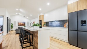 A modern kitchen with a central island, black refrigerator, and wooden flooring.