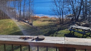 Blick auf einen See mit einer Holzterrasse, einem Picknicktisch und einer Feuerstelle.