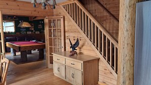 Ein Holzinnenraum mit Billardtisch, einer Treppe und einem Schrank mit Schubladen.