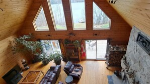 Ein geräumiger Loft-Raum mit hohen Decken, großen Fenstern, einem Steinkamin und einer gemütlichen Sitzecke.