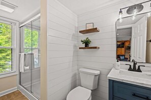 Ein modernes Badezimmer mit Duschkabine aus Glas, einer weißen Toilette und einem Waschtisch mit Marmorplatte.