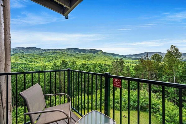 A balcony with a view of green hills and a 'No Grilling' sign.