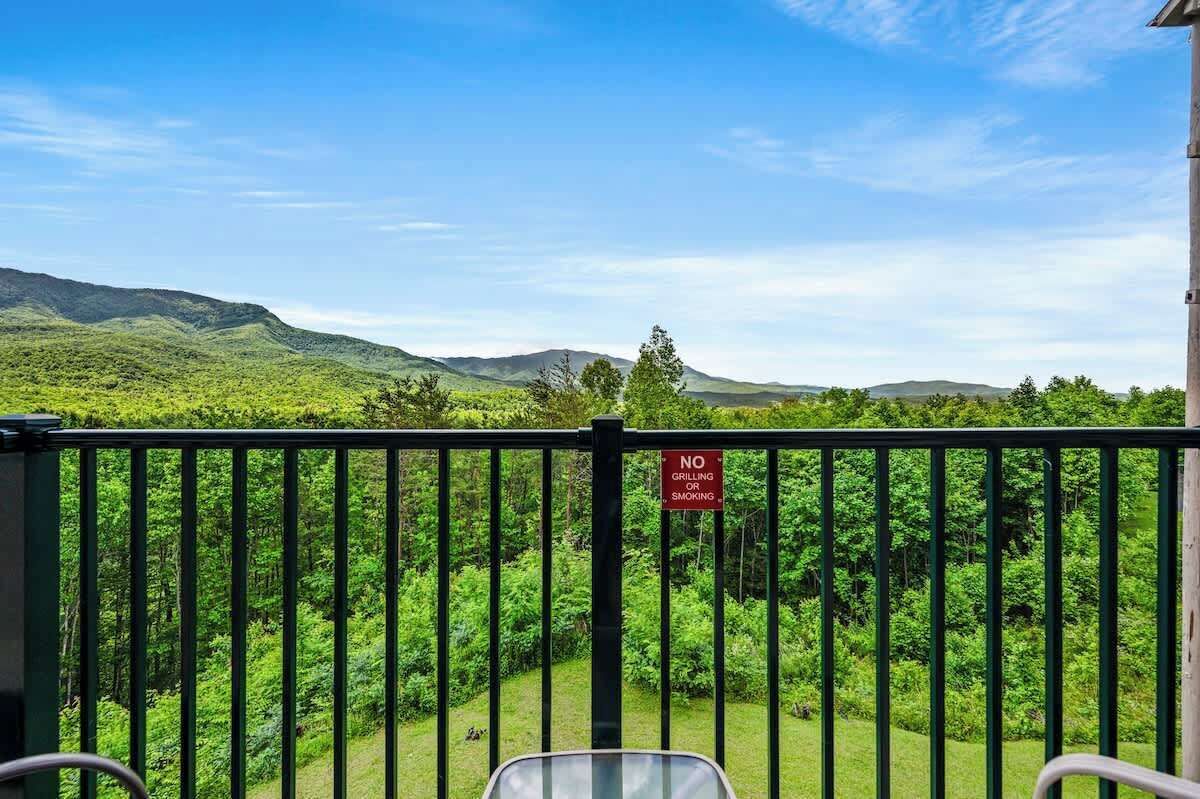 Ein Balkon mit einem Schild, das das Grillen und Rauchen verbietet, mit Blick auf eine üppige grüne Landschaft und Hügel.
