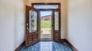 Un couloir avec une porte en bois donnant sur un espace verdoyant.