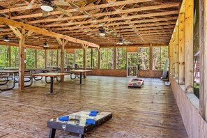 Un pabellón al aire libre con vigas de madera y techo alto, mesas de picnic y una mesa de fútbol de mesa.