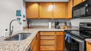 Eine Küche mit Granit-Arbeitsplatten, Holzschränken und modernen Edelstahlgeräten, einschließlich einer Mikrowelle.