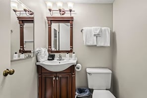 Une salle de bain avec un lavabo, deux miroirs, un porte-serviettes et des toilettes.
