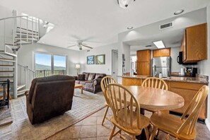 A modern kitchen with wooden cabinets, a stainless steel refrigerator, and a dining area with a round table and wooden chairs.