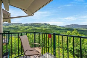A balcony with a chair and a table, overlooking a mountainous landscape.