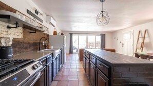 A modern kitchen with a central island, stainless steel appliances, and a rustic wall design.