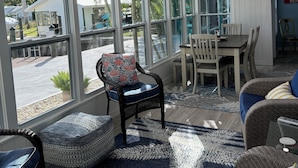 A sunroom with large windows, wicker furniture, a ceiling fan, and a dining area.