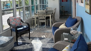 A sunlit room with a dining table, chairs, and a ceiling fan.