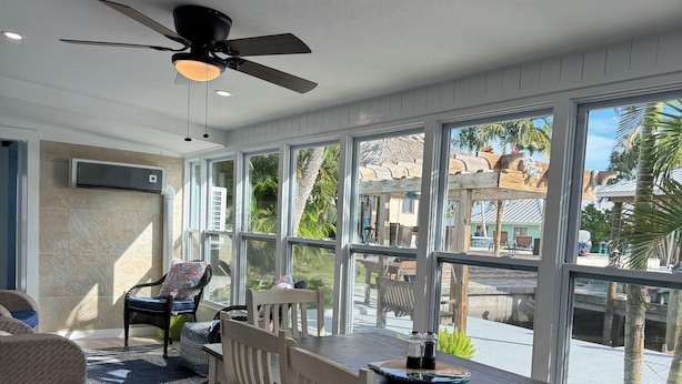 A spacious dining area with a large table, chairs, and a ceiling fan.