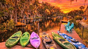 A row of kayaks and chairs on a wooden dock by a calm river at sunset. - Swim Mat, Kayaks, Fire Pit! PET FRIENDLY - Sunfish Cove - Weeki Wachee River (Weeki Wachee)