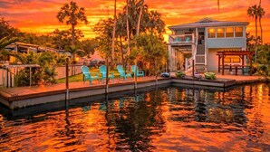 A pool area with chairs, a house, and palm trees. - Swim Mat, Kayaks, Fire Pit! PET FRIENDLY - Sunfish Cove - Weeki Wachee River (Weeki Wachee)