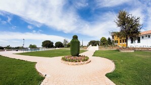 Un camino de ladrillo circular que conduce a una escultura verde central rodeada de flores.