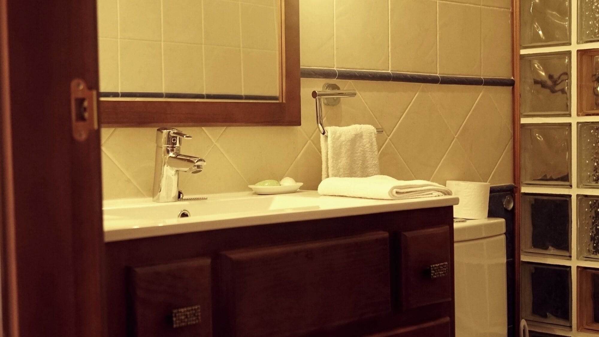 A bathroom with a white sink, a mirror, a towel rack, and a glass shower enclosure.