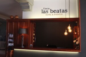 Una zona de recepción con un cartel que dice "Finca las beatas HOTEL & EVENTOS".