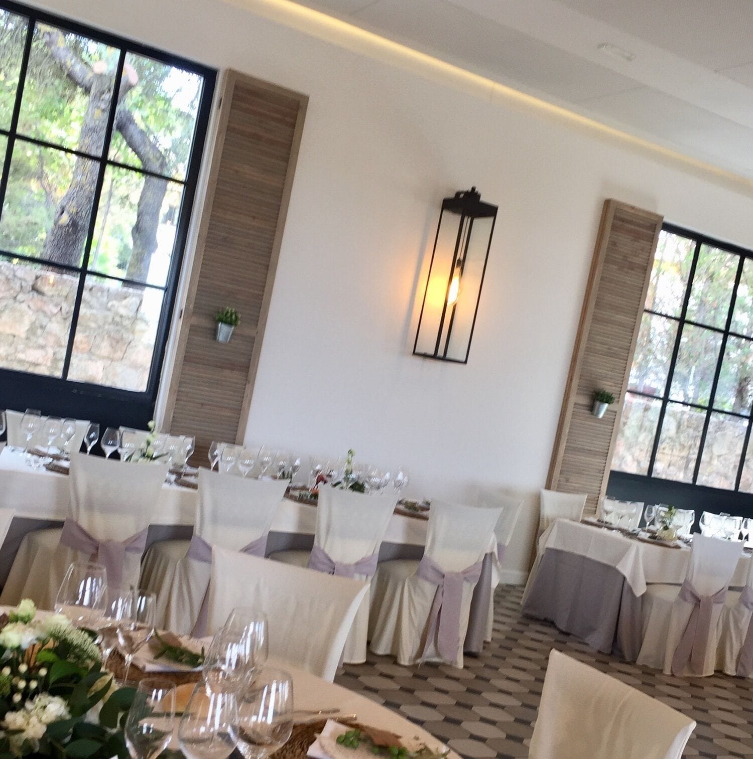 A banquet hall with tables set for a formal event, featuring white tablecloths, glassware, and floral centerpieces.