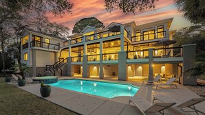 A multi-story house with a swimming pool, outdoor seating, and a staircase leading to the upper levels. - 9 Juniper @ Forest Beach | Oceanfront | Pool & Spa | 6 King Suites (Hilton Head Island)
