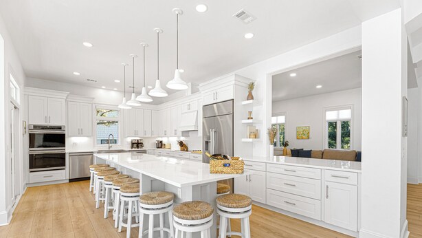 A modern kitchen with white cabinetry, a large island with stools, stainless steel appliances, and pendant lighting. - 9 Juniper @ Forest Beach | Oceanfront | Pool & Spa | 6 King Suites (Hilton Head Island)