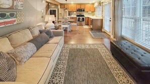 A spacious living area with a sofa, a dining table, and a kitchen in the background.