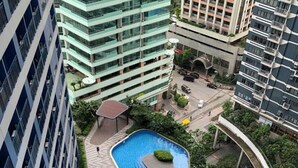 A rooftop swimming pool surrounded by lounge areas and greenery, with high-rise buildings in the background. - 1 Bedroom with Balcony Condo Apartment in Makati City (Makati)