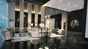 A modern interior with a reflective floor, a central seating area with sofas and tables, and a large circular light fixture on the ceiling. - 1 Bedroom with Balcony Condo Apartment in Makati City (Makati)