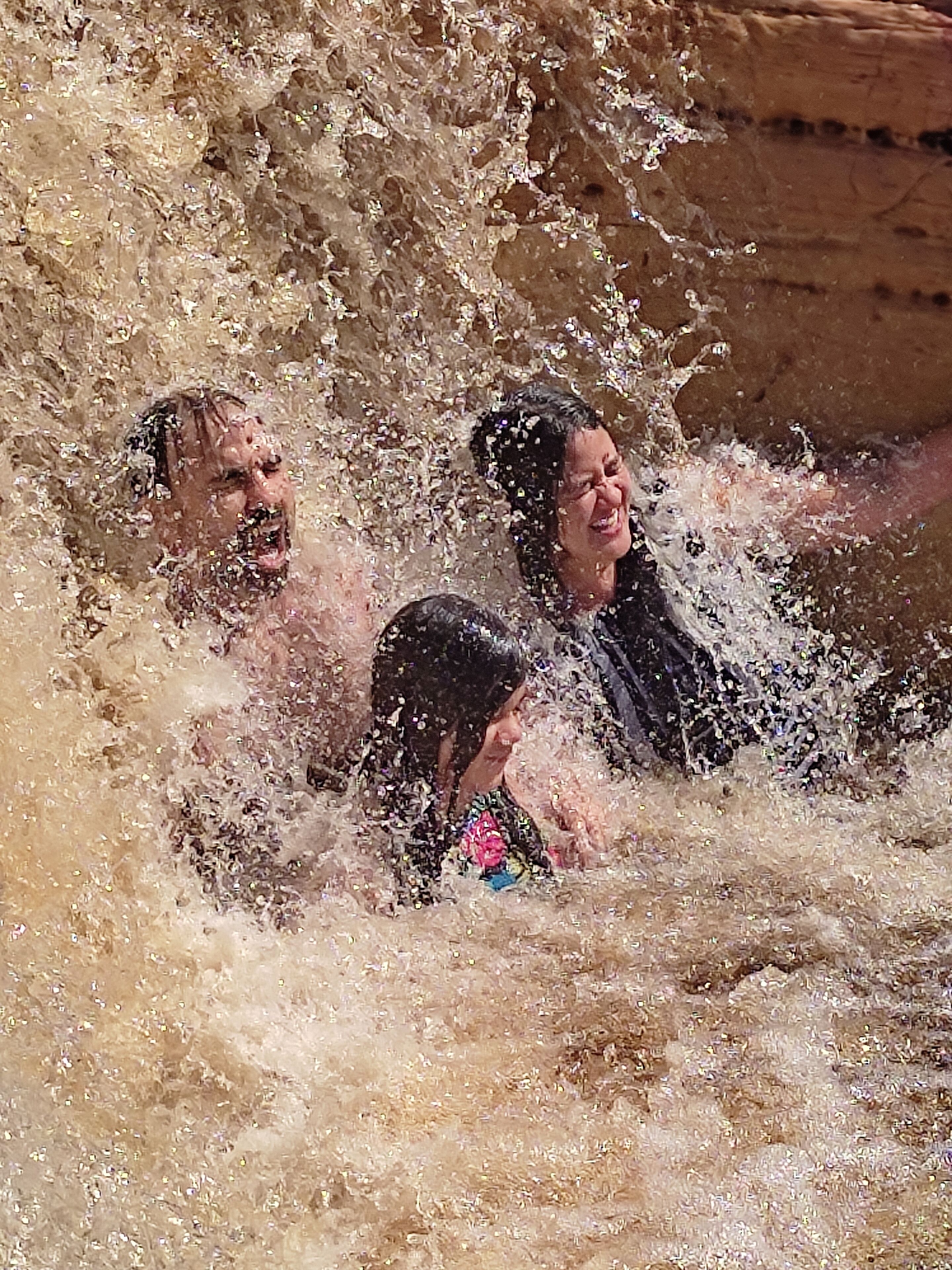 Eine dreiköpfige Familie in einer natürlichen Wasserlandschaft, vermutlich ein Fluss oder Bach.